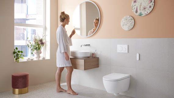 Kvinne på badet med Geberit AquaClean Alba – et kostnadseffektivt dusjtoalett med dusjfunksjon.