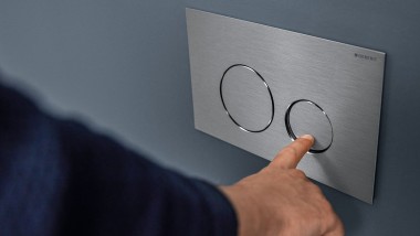"Hånd aktiverer liten spyling på Sigma40 rund betjeningsplate (© Geberit)