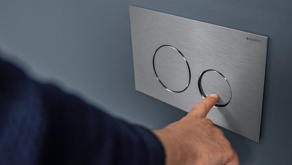 "Hånd aktiverer liten spyling på Sigma40 rund betjeningsplate (© Geberit)