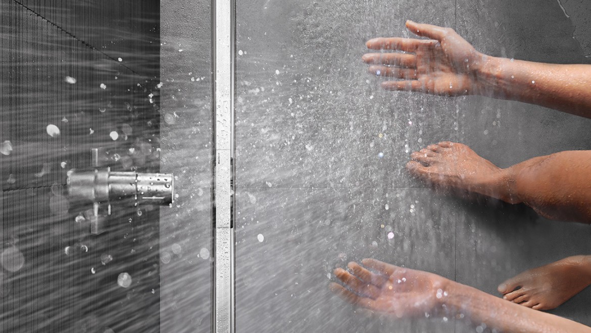 Person som dusjer i en gulvjevn dusj med Geberit CleanLine-slukrenne