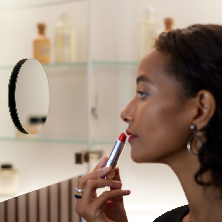 Kvinne som sminker seg i speilet