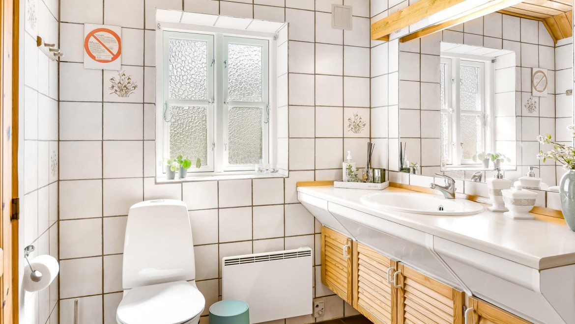Originalt bad med gulvstående toalett, hvite fliser og baderomsmøbler i tre (© @triner2 og @strandparken3)