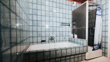 Bad med blå fliser, dusjkabinett og badekar