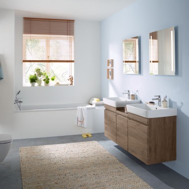 Familiebad med lyseblå vegger og baderomsmøbler i hickory, speilskap, betjeningsplate og toalett fra Geberit