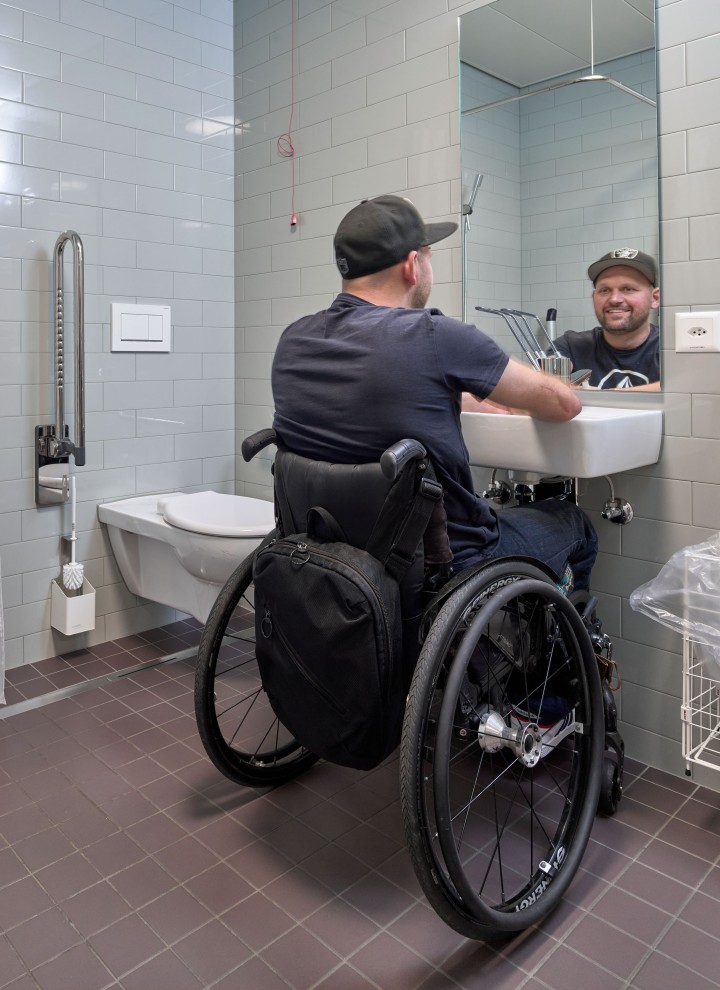 Peter Roos i rullestol ved servantområdet på badet (© Ben Huggler)