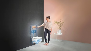 Kvinne som aktiverer spylingen på Geberit WC-systemet (© Geberit)