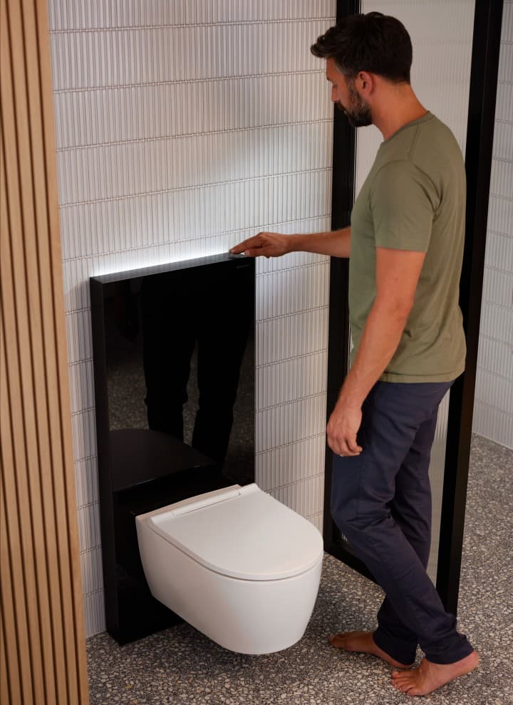 Mann ved siden av Geberit Monolith Plus med ComfortLight.