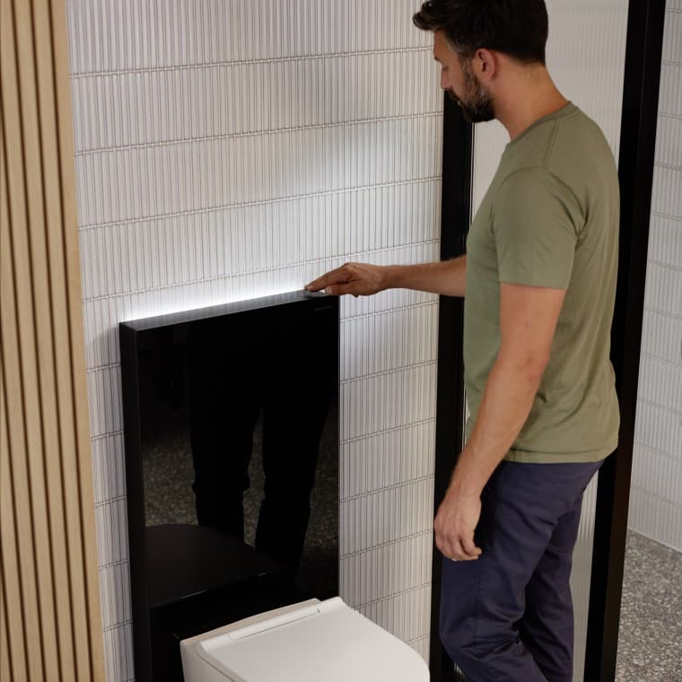 Mann som står ved siden av Geberit Monolith Plus sanitærmodul Mann som står ved siden av Geberit Monolith Plus sanitærmodul